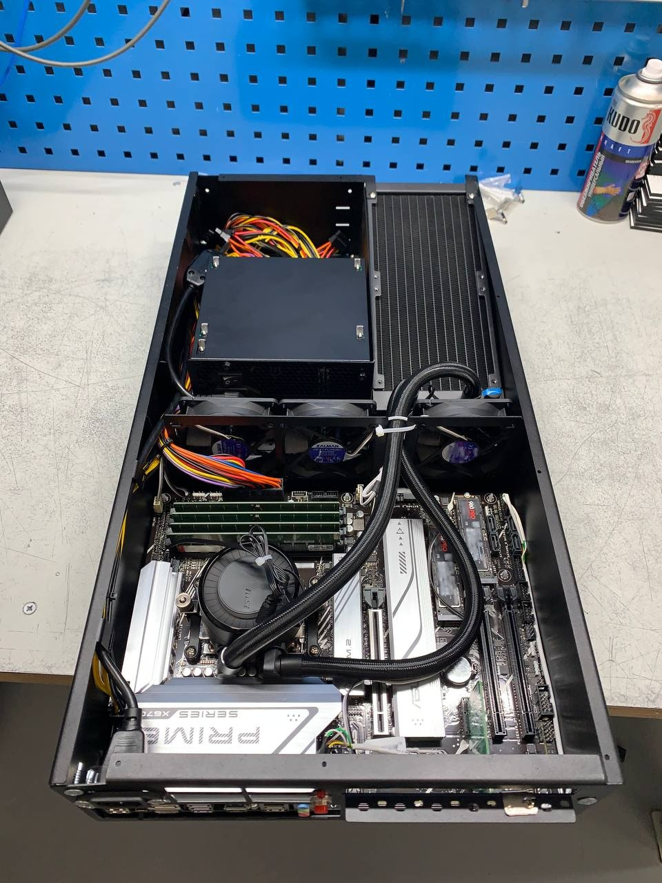 Собранный сервер в корпусе Slim Tower со снятой боковой панелью. Внутри видны материнская плата, двухсекционный радиатор системы жидкостного охлаждения с вентиляторами и аккуратно уложенные кабели.