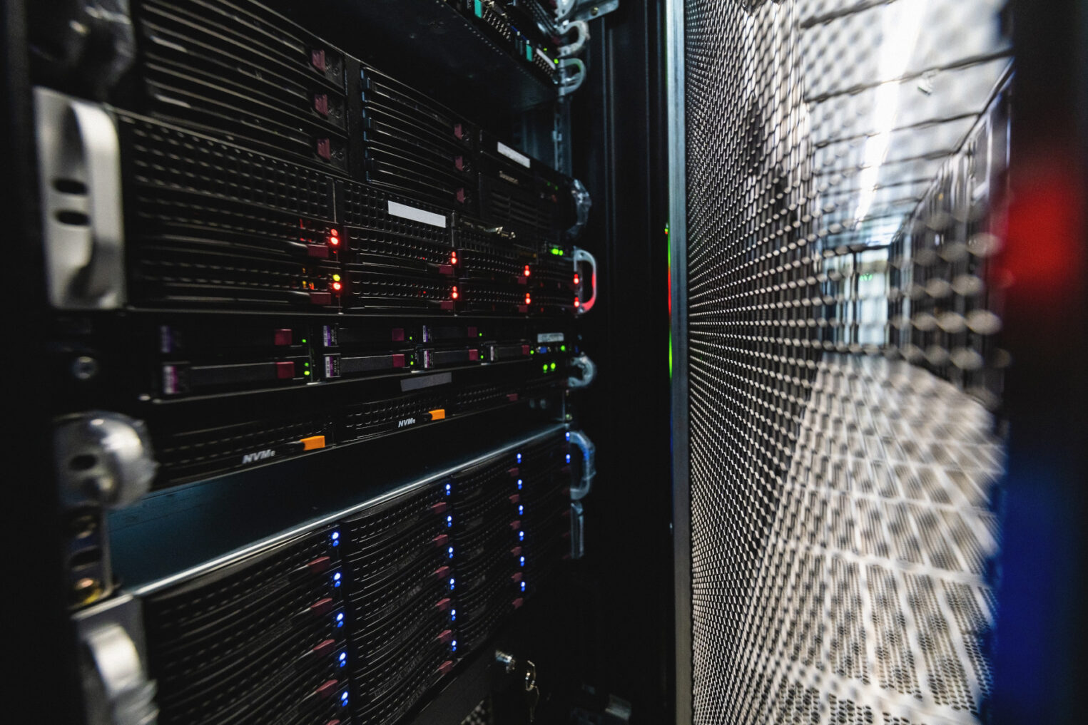 За приоткрытой решеткой серверной стойки видно работающее высокотехнологичное оборудование.