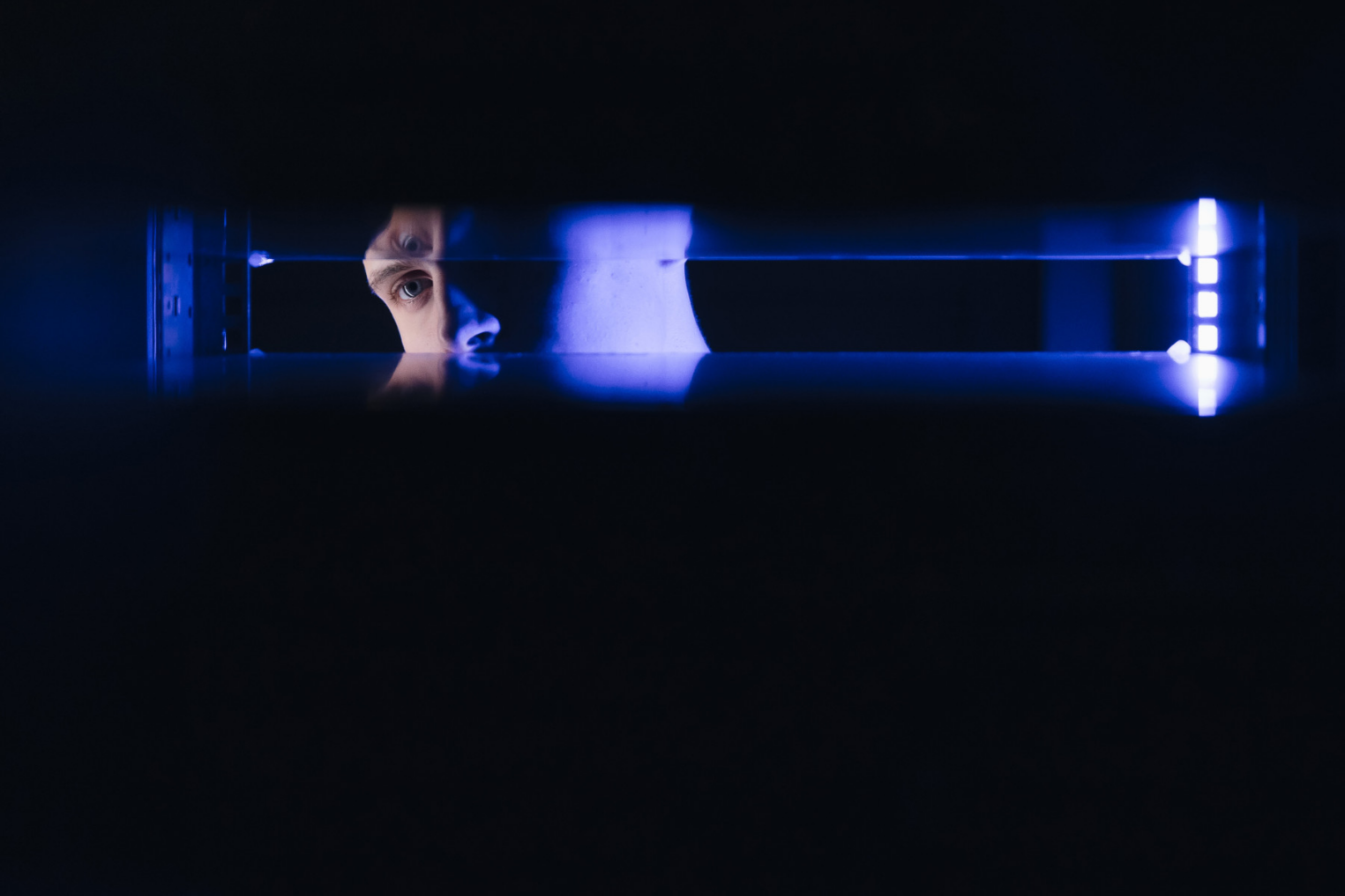 Человек смотрит в темную пустоту пространства для оборудования в серверной стойке.