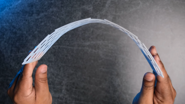 Руки человека демонстрируют гибкость пластиковой пластины (плейта) для клавиатуры.