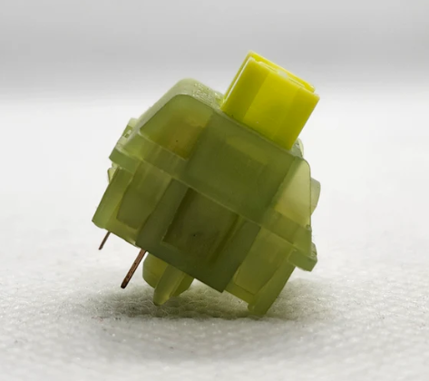 Механический переключатель зеленого цвета: видны пять ножек для крепления к печатной плате.