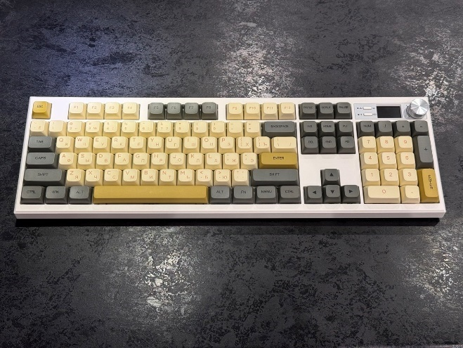 Общий план собранной кастомной клавиатуры крупным планом: установлены серо-бежевые колпачки с золотистыми акцентами.