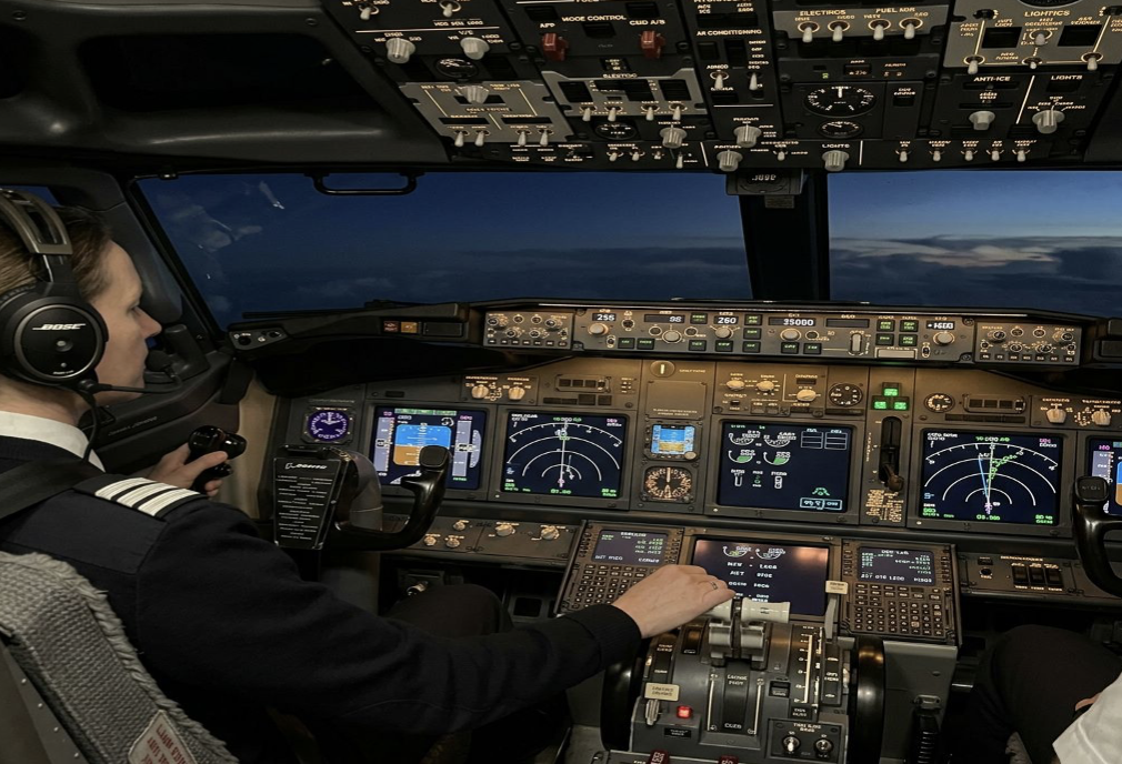 Пилот управляет самолетом ночью за штурвалом в кабине.